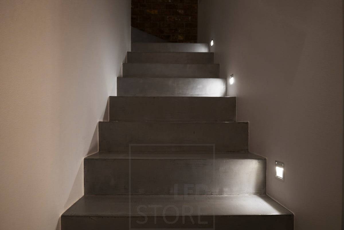 Toutes les trois marches, un luminaire mural éclaire les marches.